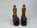 pair of wooden figurines of a man and a woman sitting on a horse
