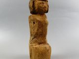 a wooden sculpture of a woman sitting on a stool