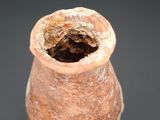 a brown vase with a hole in it on a black surface