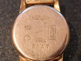 a close up of a gold watch on a black surface