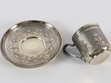 pair of silver plated cups and saucer on a white surface