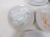 three white plates with drawings of animals on them on a table
