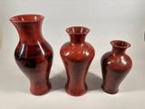 three red vases sitting next to each other on a table