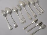 un grand nombre de cuillères et de fourchettes en argent disposées sur une table