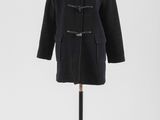 un manteau noir posé sur un mannequin, devant un fond blanc