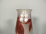 a glass vase with flowers and leaves painted on it