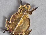 an image of a gold brooch with a sword and shield on it