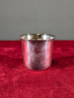 une petite coupe en argent posée sur un tissu rouge