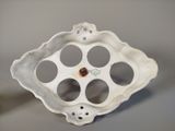 a white vase with holes in it sitting on a table