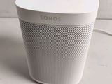 a white speaker sitting on top of a table next to a wall