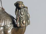 a bronze statue of a man riding a camel