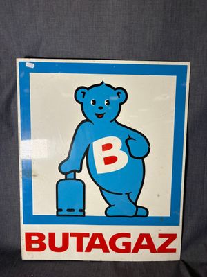 une pancarte bleue et blanche représentant un ours tenant une valise