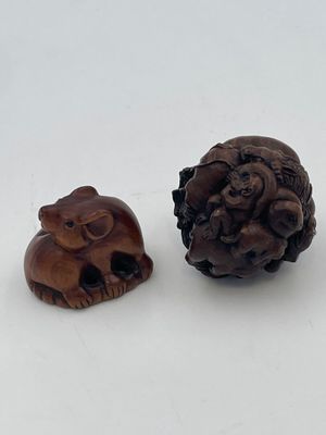 two small wooden animals sitting next to each other on a white surface