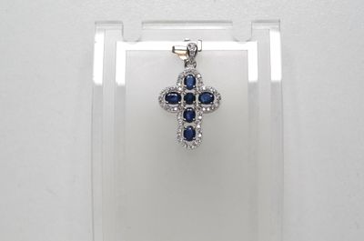 un gros plan sur un pendentif en forme de croix, orné de diamants bleus et blancs