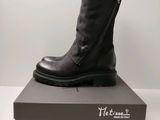 Des bottes en cuir noir avec des fermetures éclair sont posées sur une boîte