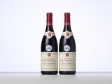 two bottles of red wine sitting on top of a table
