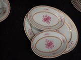 three plates with pink flowers on them on a black table