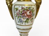 un vase blanc orné d'une anse dorée et de motifs floraux