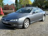 a silver car that is parked in the gravel