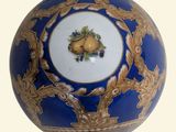 an image of a blue and gold vase with fruit on it