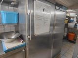 un grand réfrigérateur en acier inoxydable dans une cuisine dotée de nombreux plans de travail