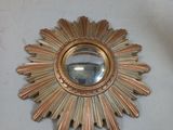 a gold sunburst with a mirror on the wall