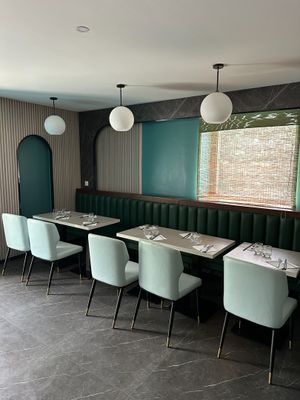 tables and chairs in a restaurant with a green wall and a window