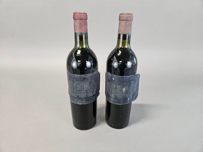 deux bouteilles de vin rouge sont posées sur une surface blanche