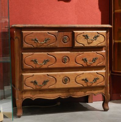 a wooden chest of drawers in a room with a clock on the wall