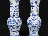 two blue and white vases with dragon designs on them on a black background