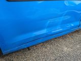 a blue car that has been dented and is parked on the side of the road