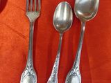 several spoons, forks, and spoon rest on an orange cloth
