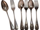 six spoons and a fork are lined up on a white surface