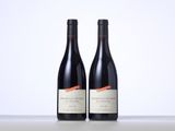 two bottles of red wine sitting on top of a table