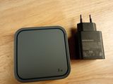une petite boîte noire avec un chargeur posée sur une table en bois