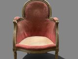 une chaise rose avec des finitions dorées et un coussin beige