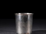 an old silver cup sitting on a table with a black background