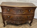 une commode ancienne posée sur un parquet dans une pièce