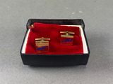 a pair of red and blue cufflinks in a black box
