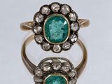 un gros plan d'une bague en or sertie de deux émeraudes