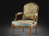 une chaise ancienne dont le dossier et les accoudoirs sont recouverts d'un tissu à motifs floraux