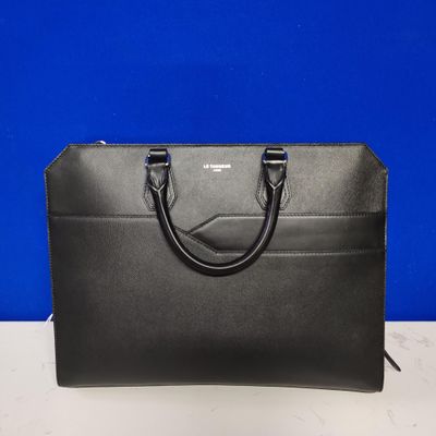 a black handbag on a table with a blue background