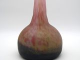 un vase rose et noir posé sur une surface blanche