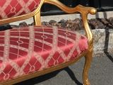 a red and gold couch sitting in front of a black fence