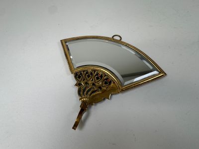 a gold fan shaped mirror hanging on a wall