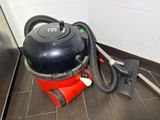 a red and black vacuum sitting on the floor