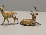 two figurines of a deer and a deer laying down on a table