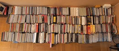 une grande pile de DVD posée par terre à côté d'un ventilateur