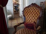 une chaise rouge et dorée dans une pièce avec une cheminée