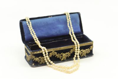 une image représentant une boîte noire avec un collier de perles sur fond blanc